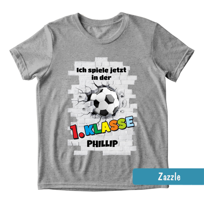Graues Schulanfangs-Shirt mit Fußball in Steinmauer & buntem Text: 1. Klasse mit personalisierbarem Namen.