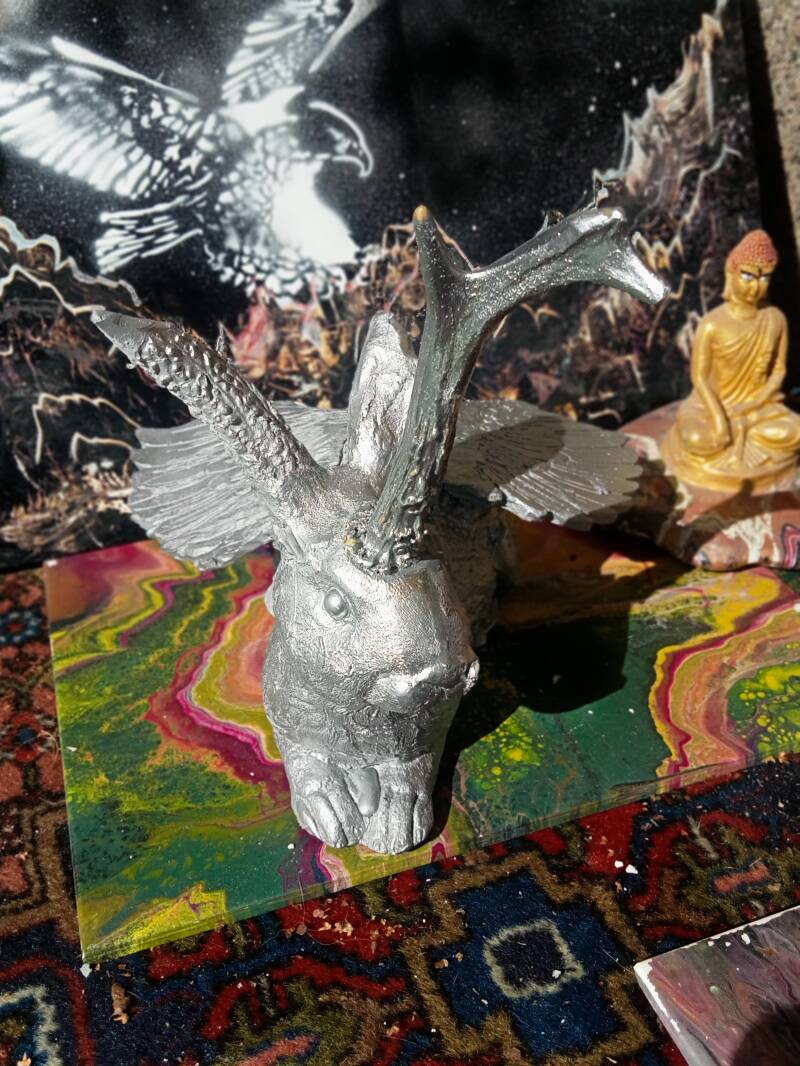 Silberner Wolperdinger aus Gips. daneben kleiner Buddha in Gold,