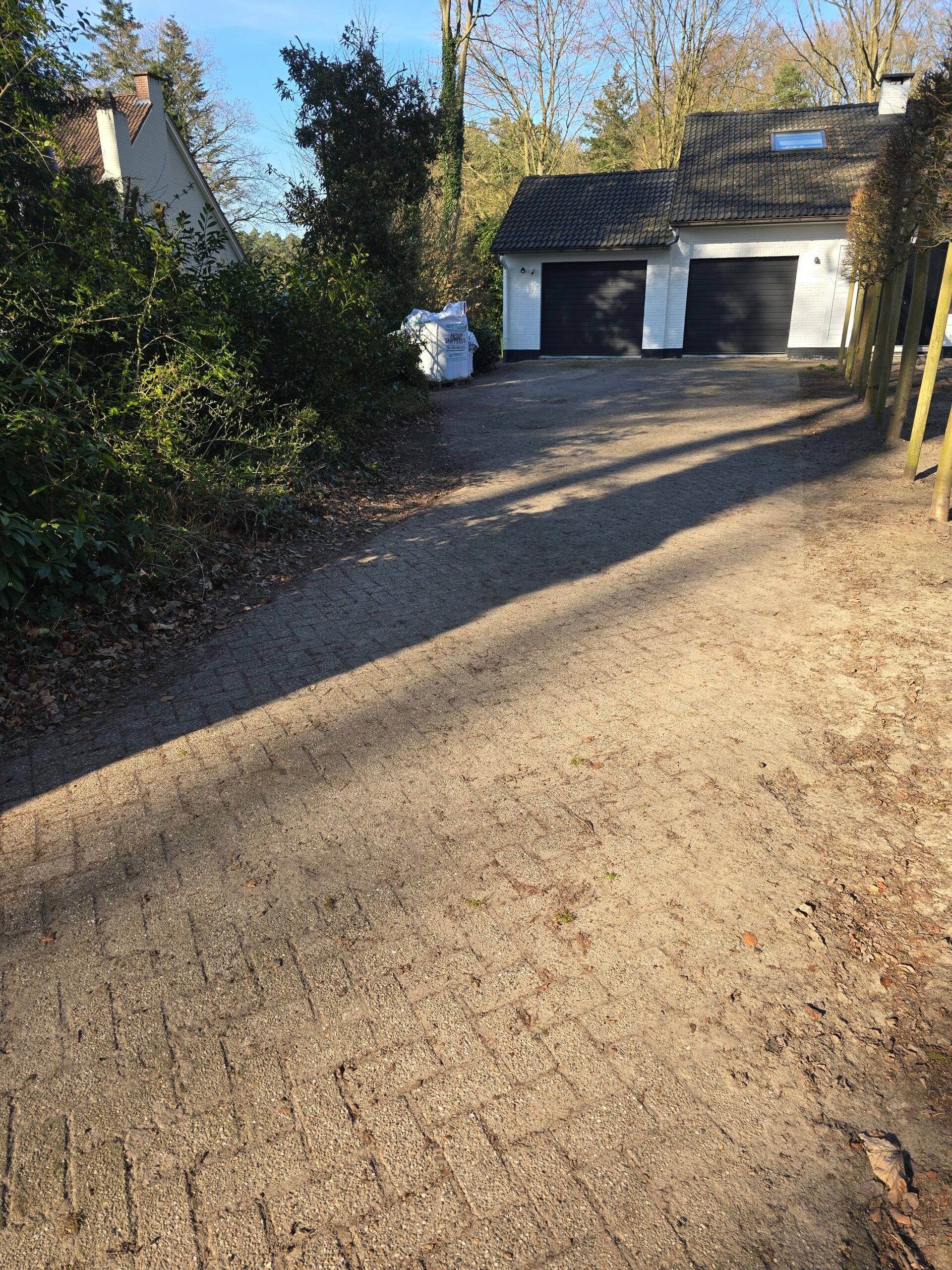Situatie vóór de werken: een uitgereden zandoprit met sporen, tussen twee hagen.