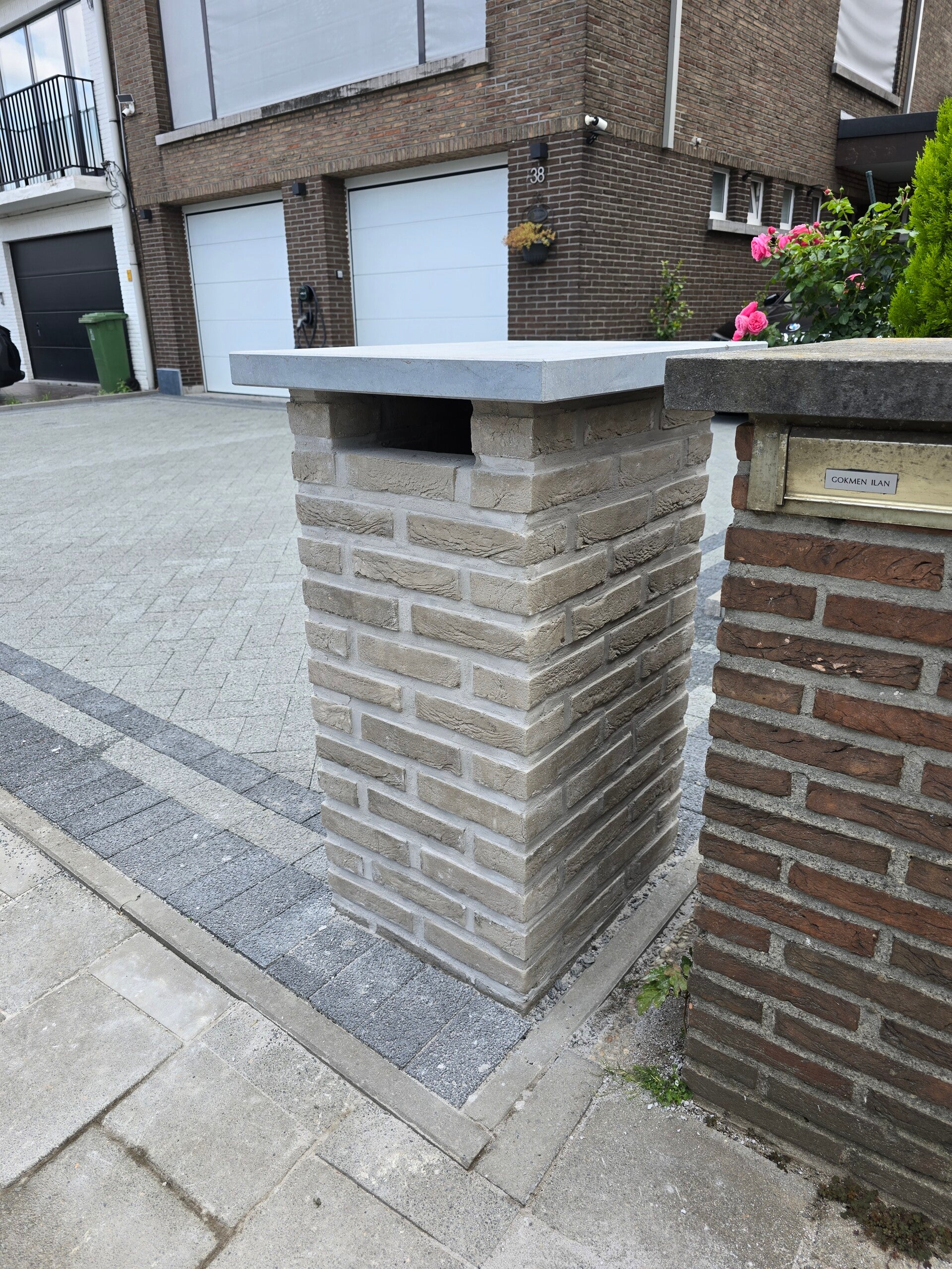 Gemetselde pilaar in gevelsteen met blauwe hardstenen deksteen, naast een nieuwe oprit.