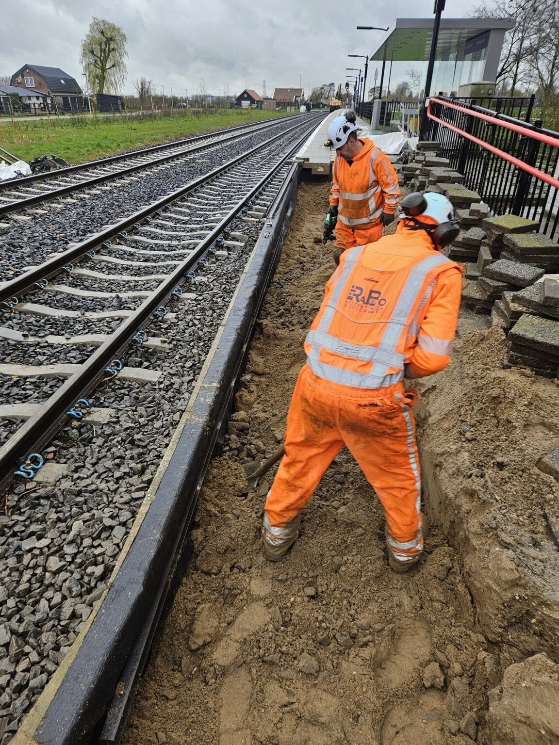 RaBo-vakmensen werken aan een hellingbaan-keerwand langs het spoor | RaBo Bestratingen & Spoorwerk B.V.