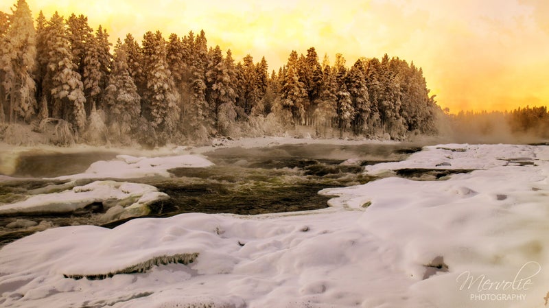 The golden light catching the mist is absolutely beautiful. The frozen cascades and snow-draped surroundings create a magical scene that feels almost otherworldly.
