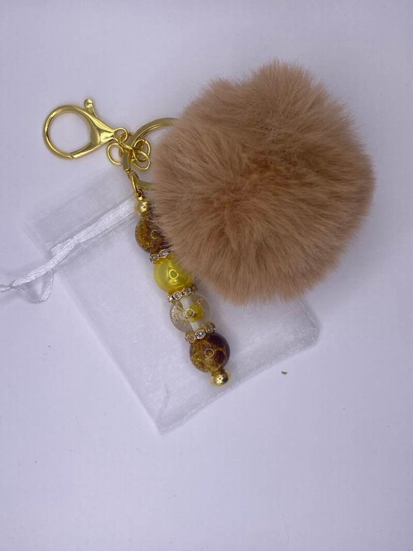 Sleutelhanger goudkleurig met beige pompom en bloemenkraal goud