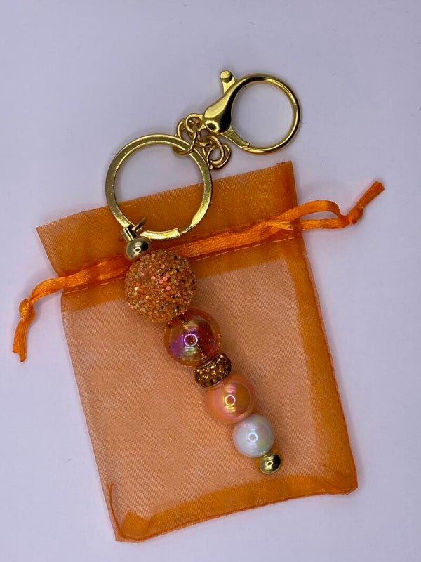 Sleutelhanger goudkleurig met oranje en parelmoer kralen