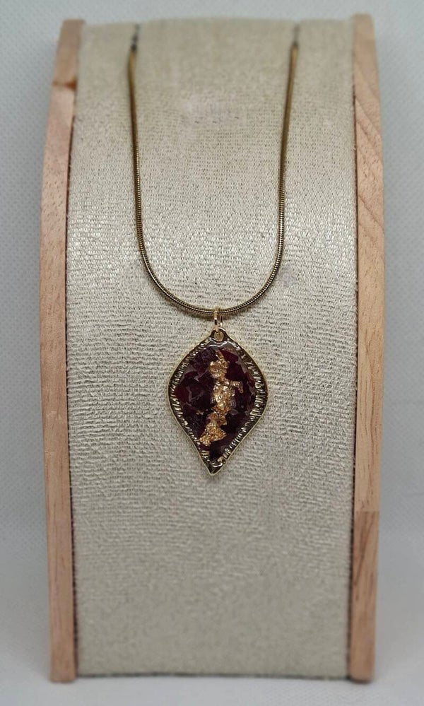 Ketting goudkleurig met druppelvormige bedel gevuld met schelpenvlokken en goudvlokjes