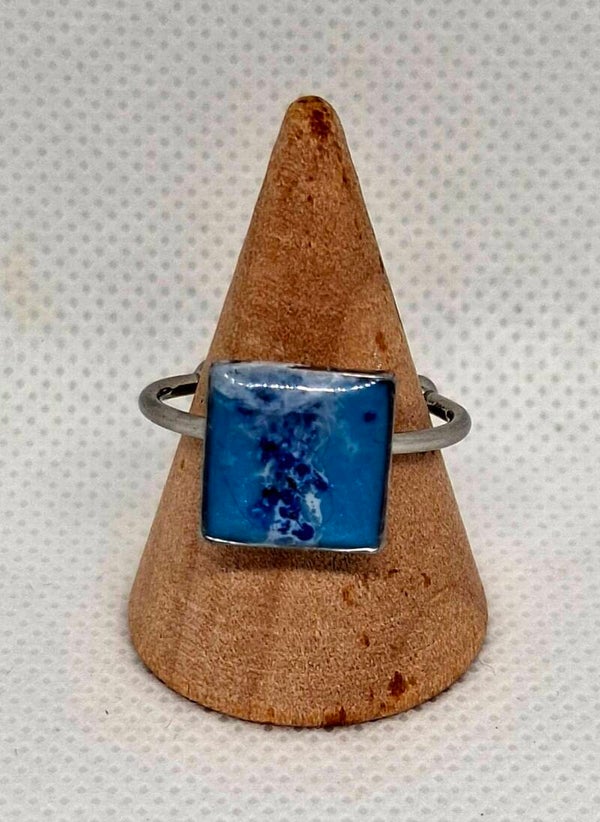 Ring zilverkleurig met vierkante bedel, gevuld met blauwe epoxy en blauwe droogbloem