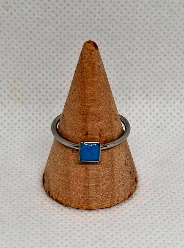 Ring zilverkleurig, met klein vierkant bedeltje gevuld met blauwe epoxy
