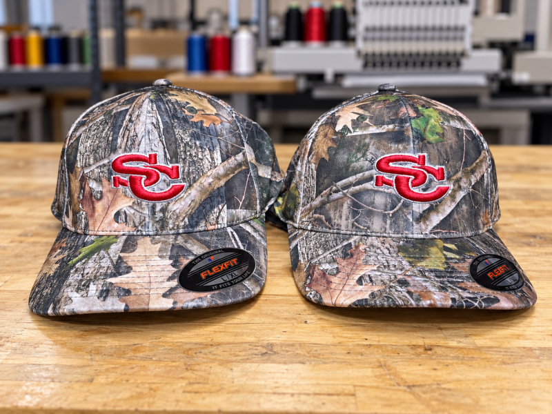 Custom embroidered camouflage Flexfit hats with red and white team monograms