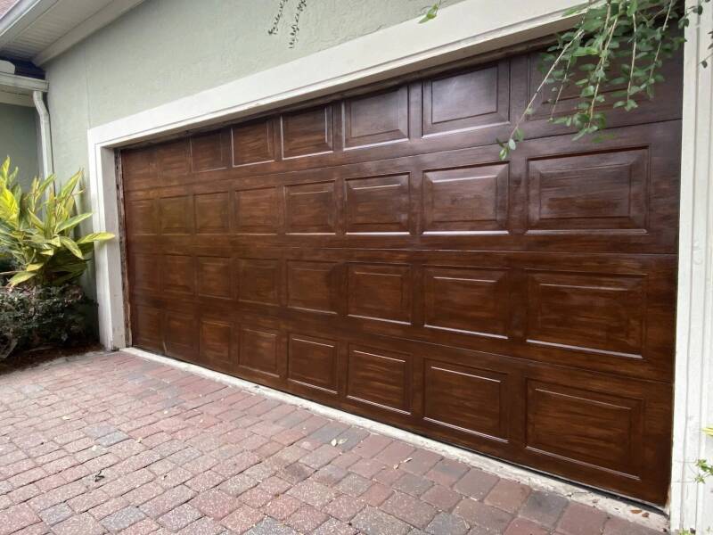 image of a garage door that has been finished to replecate the warm appearance of natural wood grain