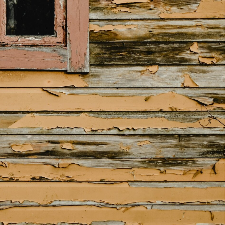 old house siding with peeling paint and visible wood rot