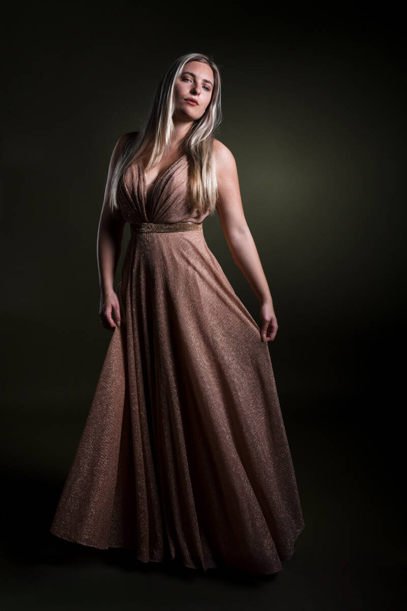 Fine Art Portret  met een mooie jonge dame met practig strak blond haar en stralend blauwe ogen. Ze draagt een roze glitter jurk ze voor een groene achtergrond