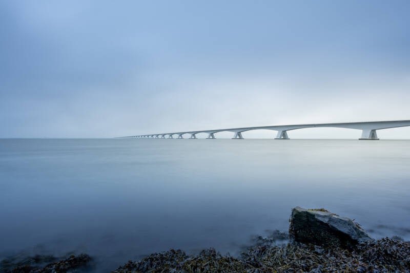 Fine Art landschap van de Zeelandbrug tijdens de zonsopkomst. Laat je muren spreken met een prachtig verhaal vertellend landschapskunstwerk van John van de Gazelle. Want, één beeld zegt meer dan duizend woorden.