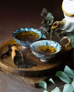 2 kopjes met oolong thee en daarnaast een lepel met oolong kruiden