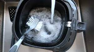 airfryer wordt schoongemaakt met water, zeep en een borstel