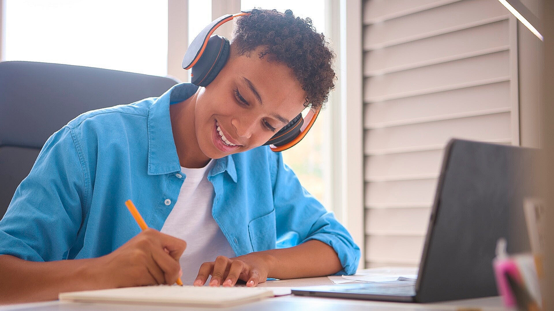 Smiling French GCSE student answering listening questions in an online tutorial.
