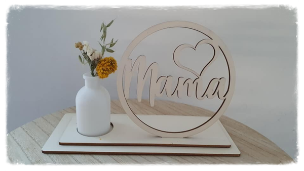 Houten cirkel met naam en vaas met droogbloemen.