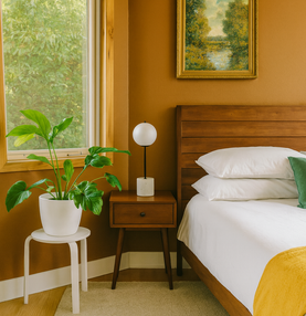 Een slaapkamer met een warme accentmuur, plant en warm houten details aan een slaapkamerraam