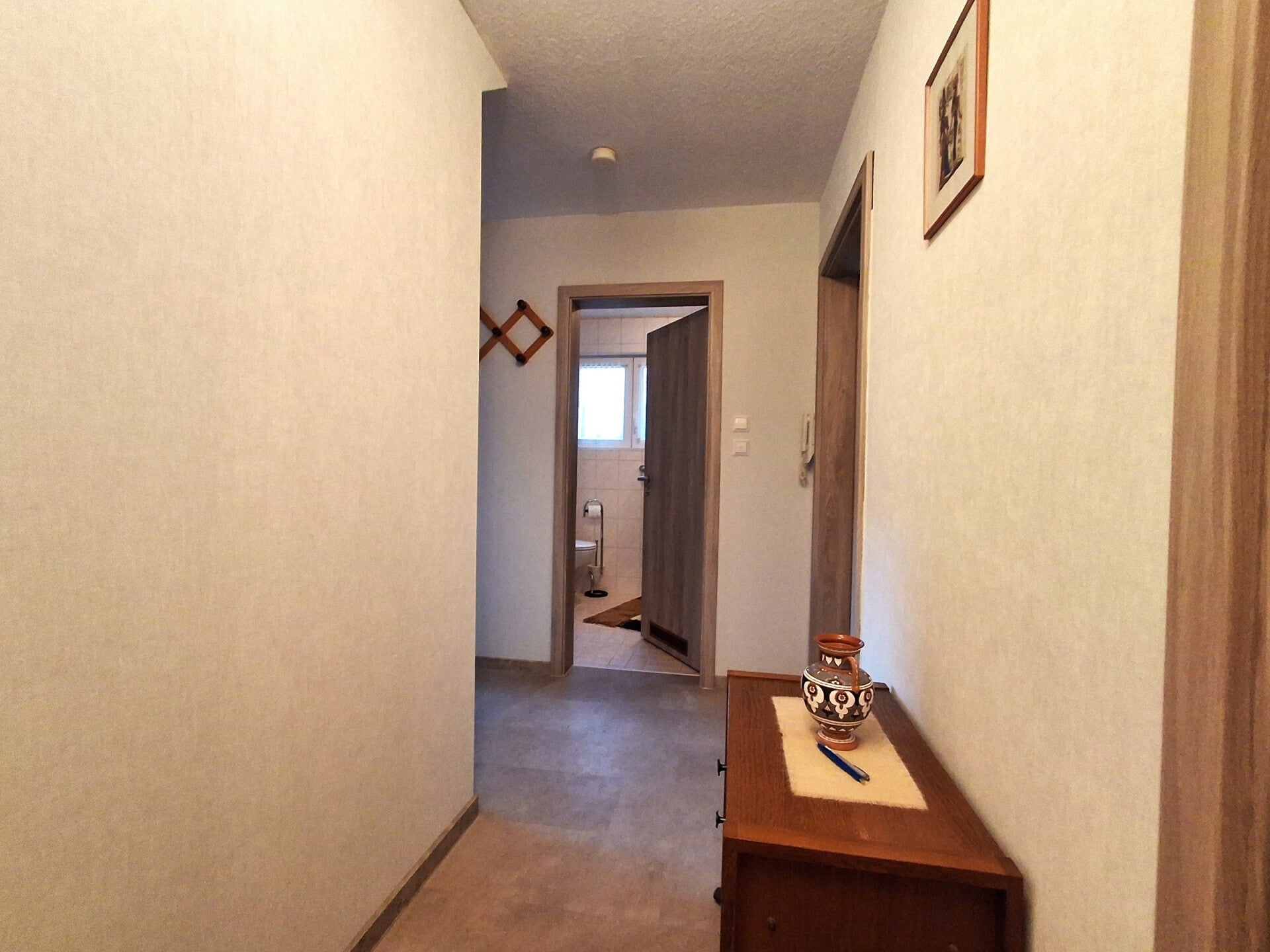 Flur mit Gardarobe, kleinem Schränkchen und Blick in das Tageslichtbad
