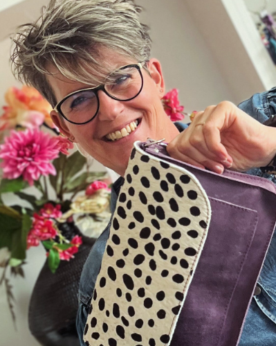 Sandra Creaties met een handgemaakte leren tas in haar handen.