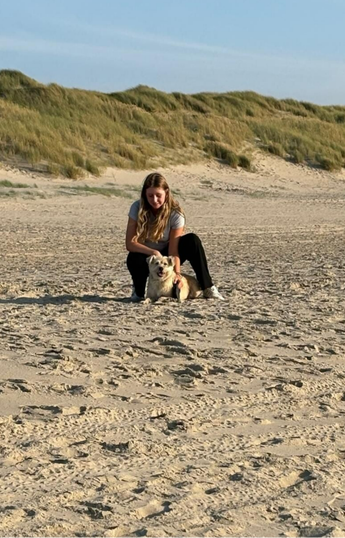 Meisje zit met hond op het strand