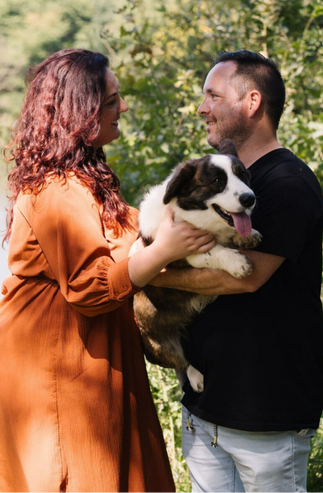 Man en vrouw kijken naar elkaar en hebben een corgi (hond) opgetild