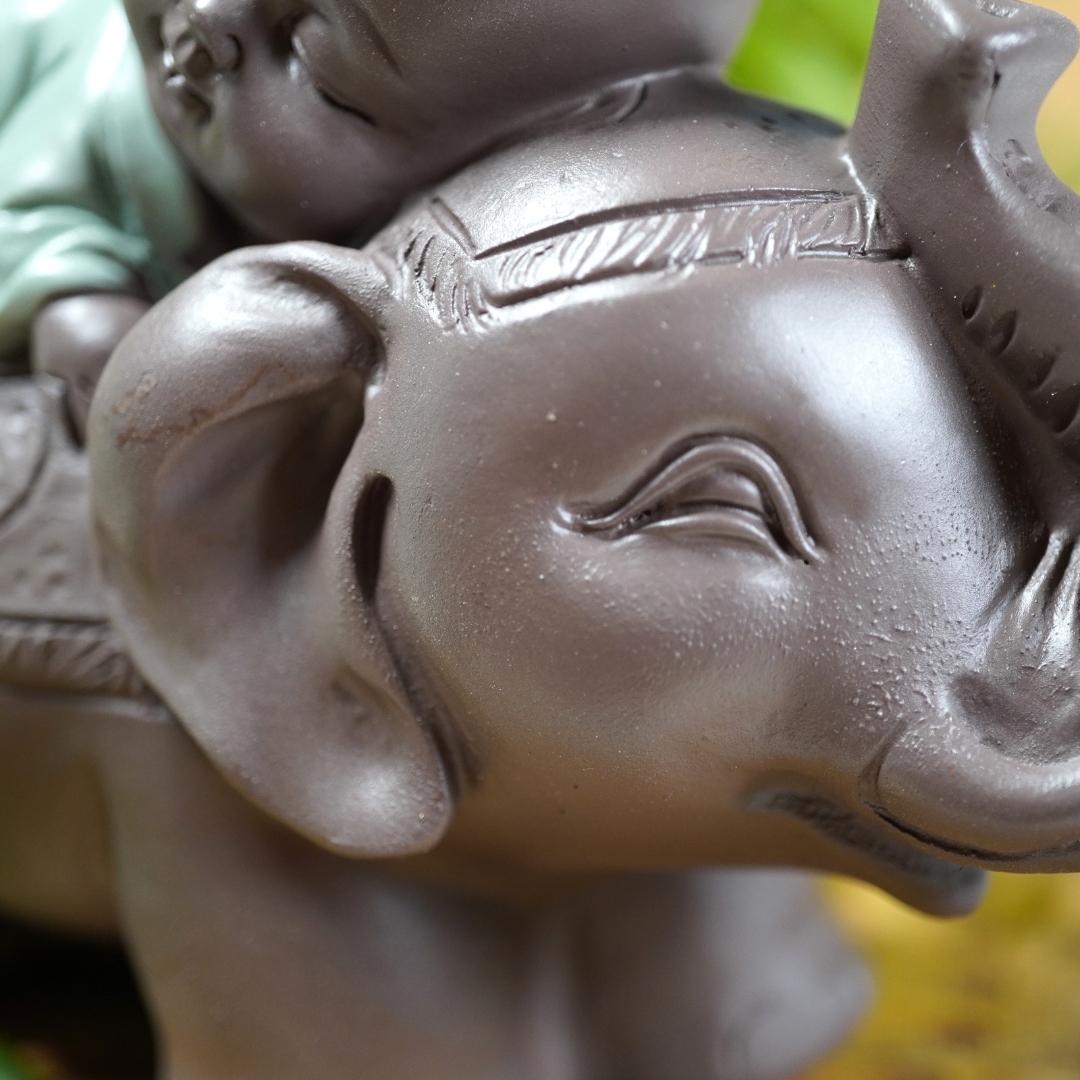 Baby monnik op de rug van een feng shui geluksolifant, beeldje van polyresin