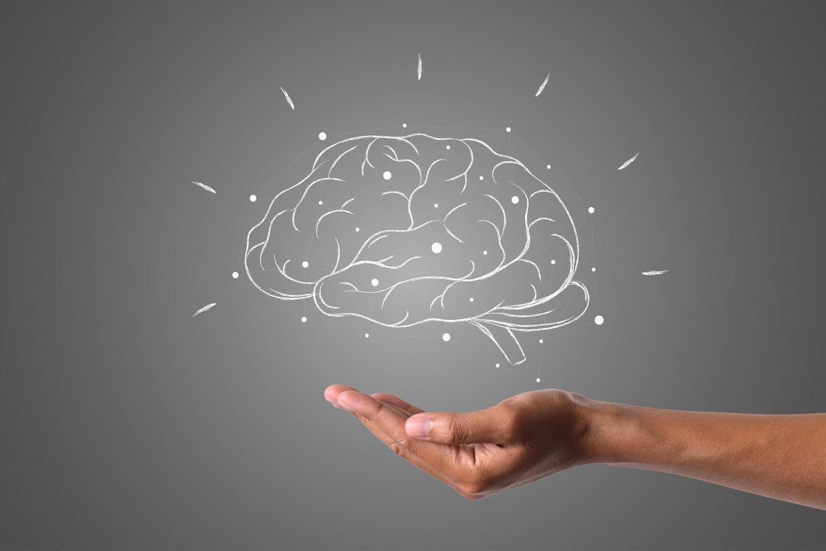 Hand einer Person hält eine gezeichnete weiße Kreidezeichnung eines Gehirns auf grauem Hintergrund, symbolisch für Denken oder Geist, Kontext Blog Mediumship & Research Institut für Medialität & Afterlife Forschung.