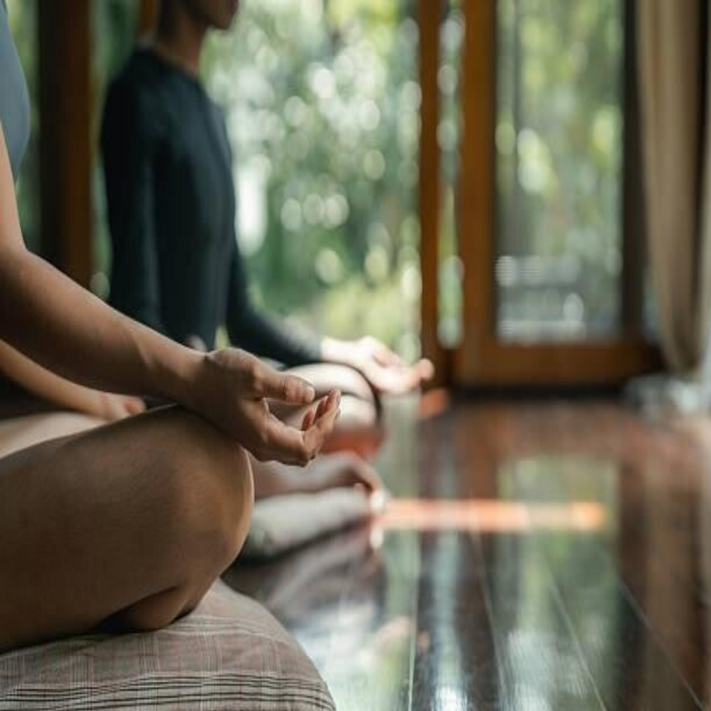 Zwei Personen sitzen im Schneidersitz auf Yogamatten. Ein Mann mit grauen Haaren trägt ein blaues T-Shirt, eine Frau mit blonden Haaren trägt ein helles Oberteil. Sie meditieren ,Kontext Blog Jenseitskontakte Jana Lorenz.
