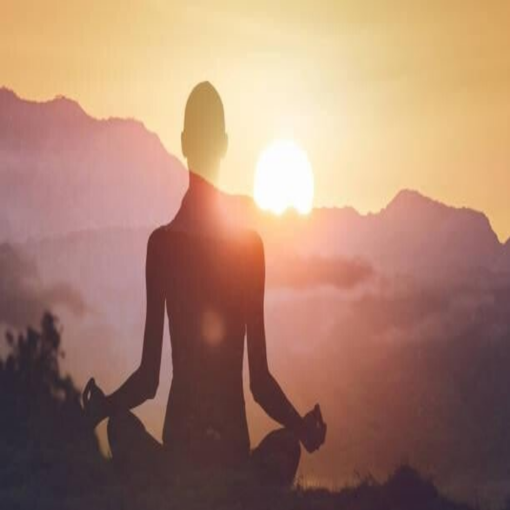 Frau sitzt im Lotussitz, Hände in Meditationsmudra, trägt weiße Kleidung, unscharfer Hintergrund, Kontext Blog Jenseitskontakte Jana Lorenz.
