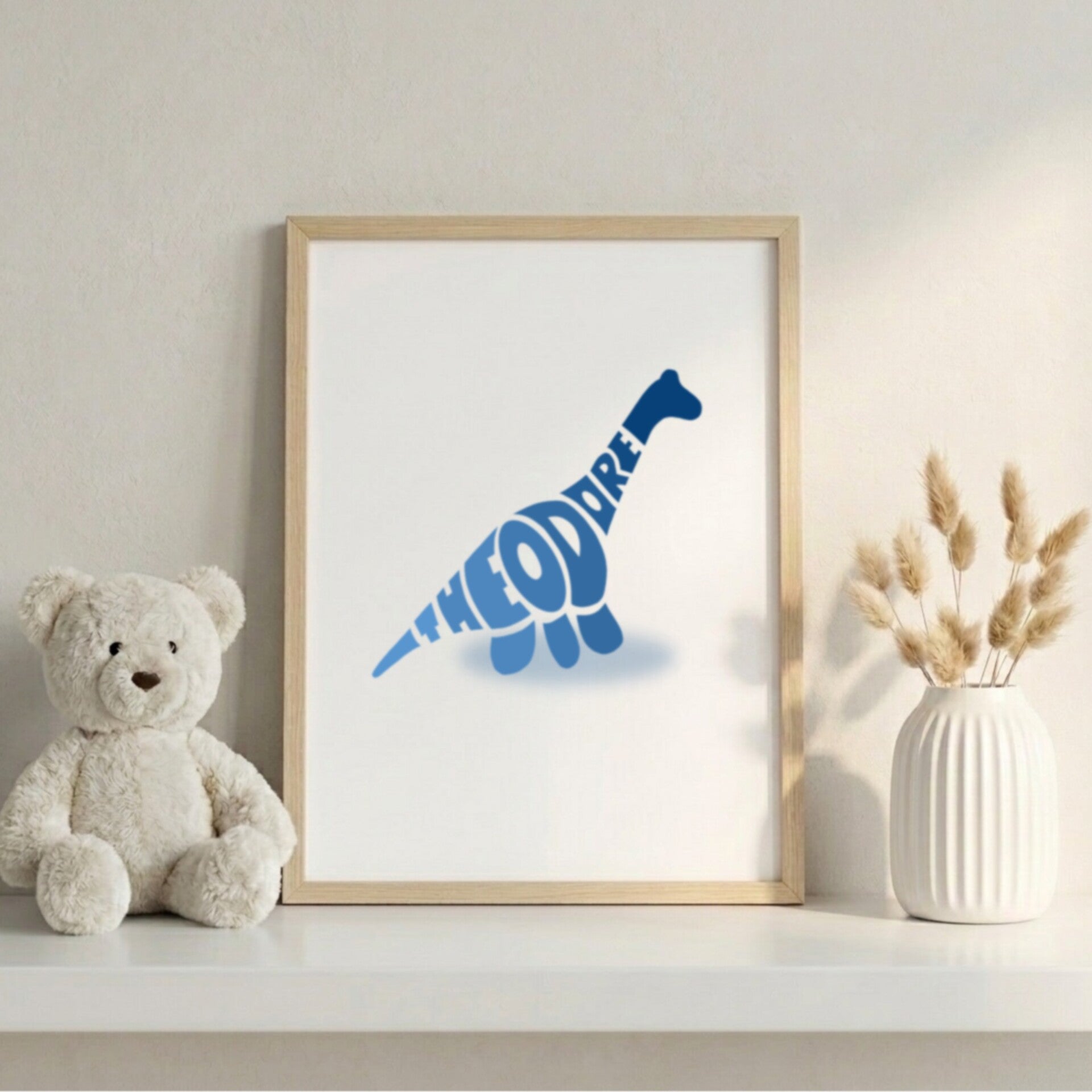 An Amber Gold typographic silhouette of a Triceratops with the name "MIA" integrated into its side. The white-framed horizontal print is displayed on a wooden sideboard in a warm, bohemian-style room next to pampas grass in a white vase.