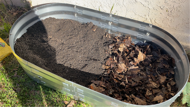 covering leaves in raised bed with soil