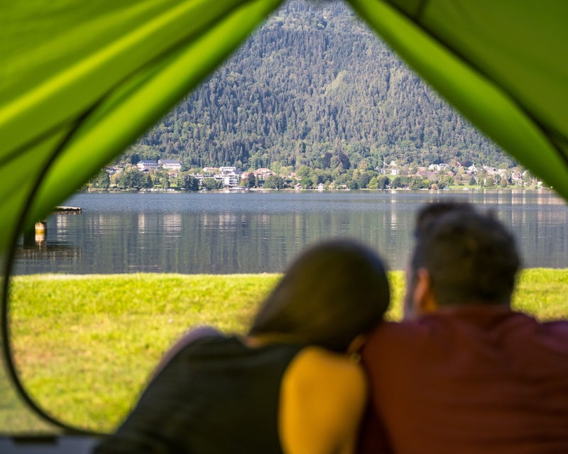 Blick vom Zelt auf den Ossiachersee – zwei Liebende genießen die Aussicht am Seecamping Lampele