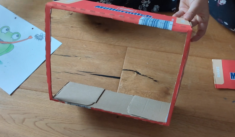 Lebensmittelkarton wird vorne aufgeschnitten, nun ist es ein kleiner Theaterrahmen