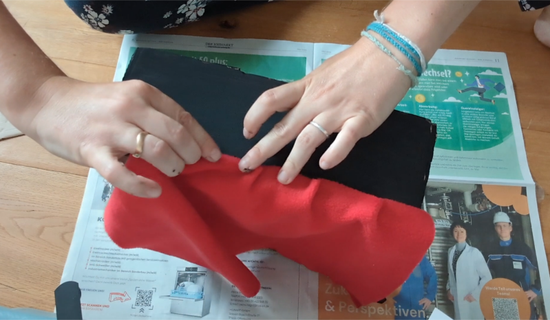 Vorhangstoff für das Kamishibaitheater wird an die Oberkante des Kamishibai-Rahmens geklebt