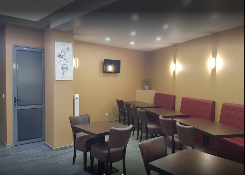 Gezellige inrichting van Safara Kebab - houten tafels en stoelen, traditionele decoraties en een kunstzinnig schilderij aan de muur.