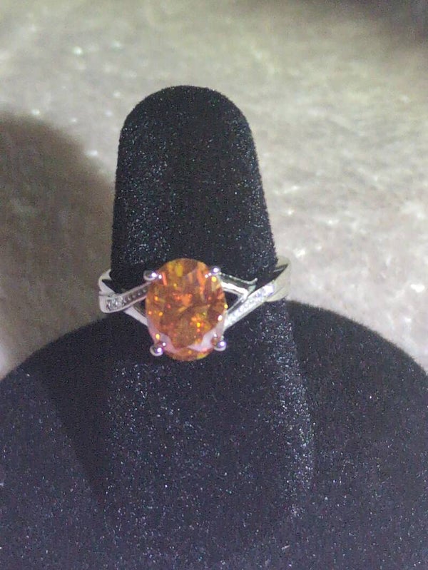 Sz 7 S925 Sterling Silver oval-cut orange moissanite set in a split-shank band accented with Moissanite stones.