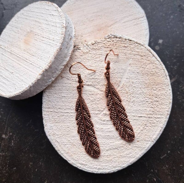 Koperkleurige boho oorbellen met veren.