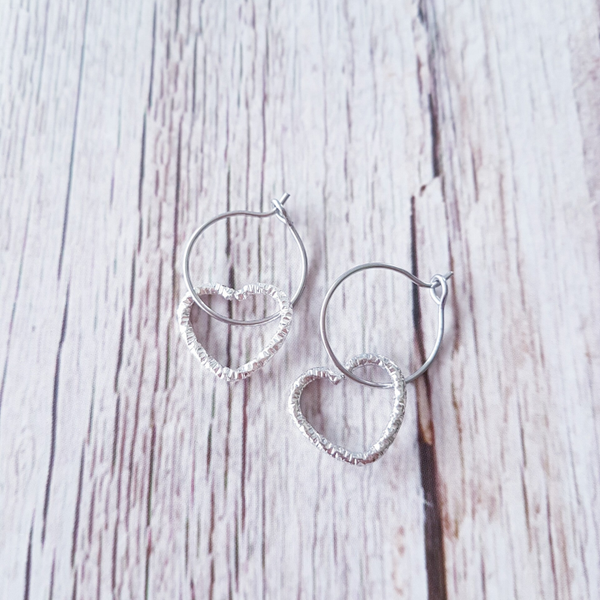 Zilverkleurige creolen met holle hartjeshanger.