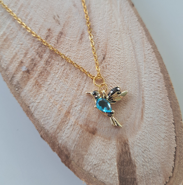 Goudkleurige halsketting met blauwe kolibriehanger.