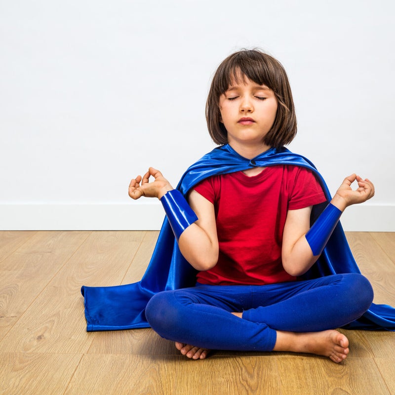 Jongen in supermanpak in yogahouding