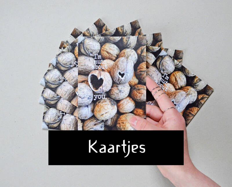 KAARTJES button; afbeelding toont een hand die een kaartje vasthoudt met walnoten op waar hartjes in geknaagd zijn