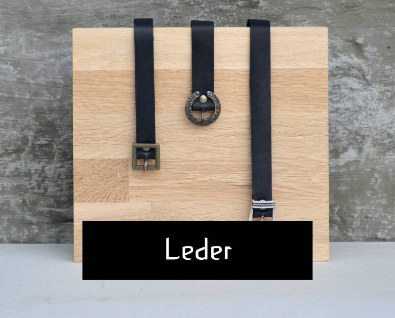 LEDER button; afbeelding toont een houten blok met drie zwart lederen chokers op in verschillende lengtes met verschillende gespen