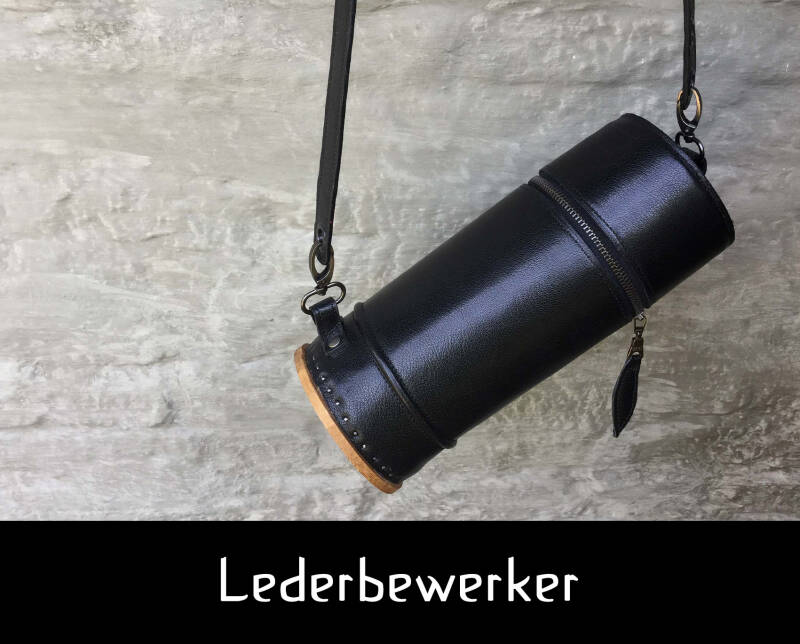 Lederbewerker ; zwarte handtas 'a roll model' voor een rustieke grijze muur