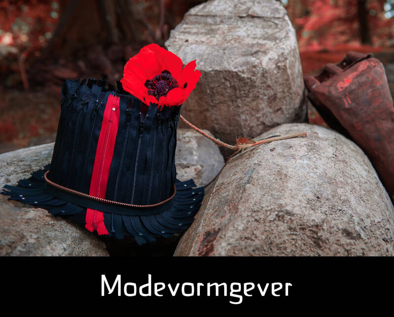 Modevormgever ; hoge hoed met zwarte en rode ritsen; poppy; grote keien
