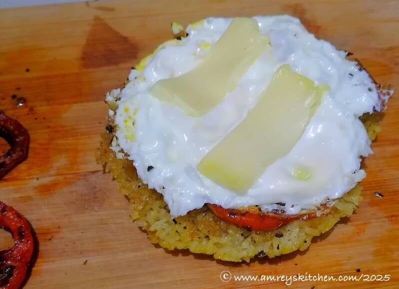 egg with cheese on top of seasoned tomato slices and toasted rice crust on a wooden board. Recipe and photo by Amrey Boquiren for Amrey’s Kitchen™.