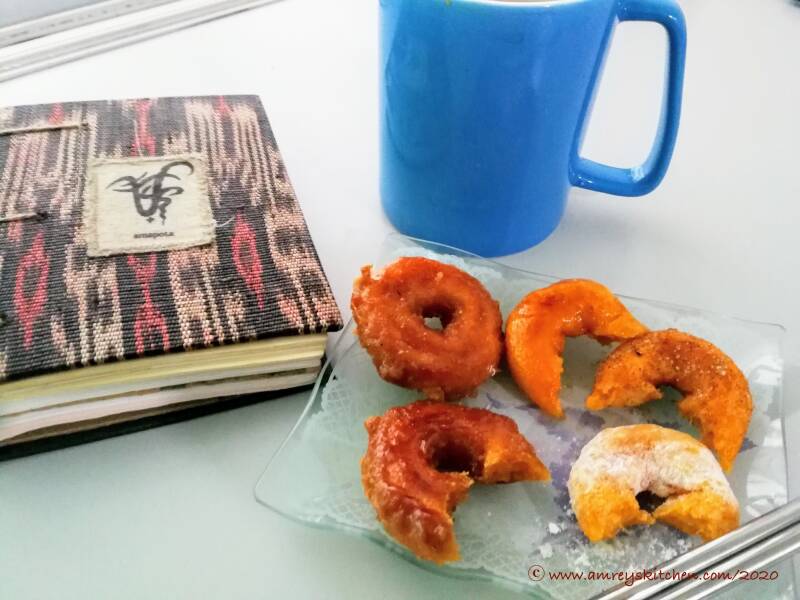Atomic Treats Kuih Keria on a clear serving dish with Kina Amapola hand-woven journal and a blue mug of brewed coffee