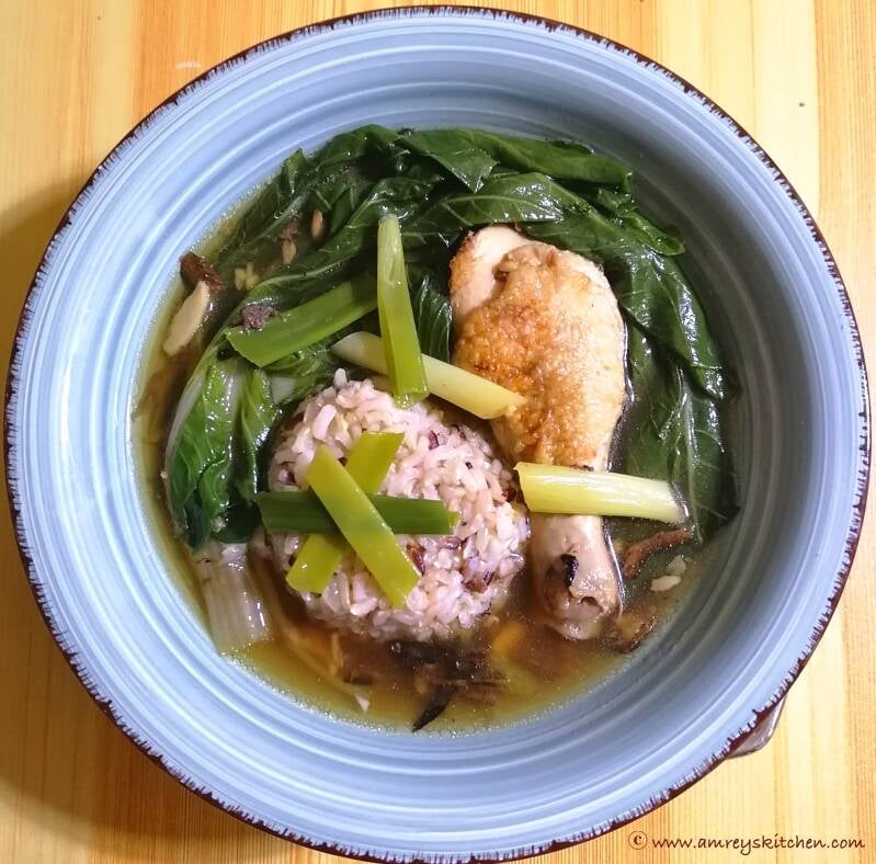 Pan-Fried Chicken Tinola with Sagada Rice in a blue ceramic bowl on a wooden table. Recipe and photo by Amrey Boquiren of Amrey’s Kitchen™.