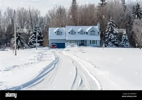 Snow being cleared from an extra-large residential driveway using heavy-duty equipment.