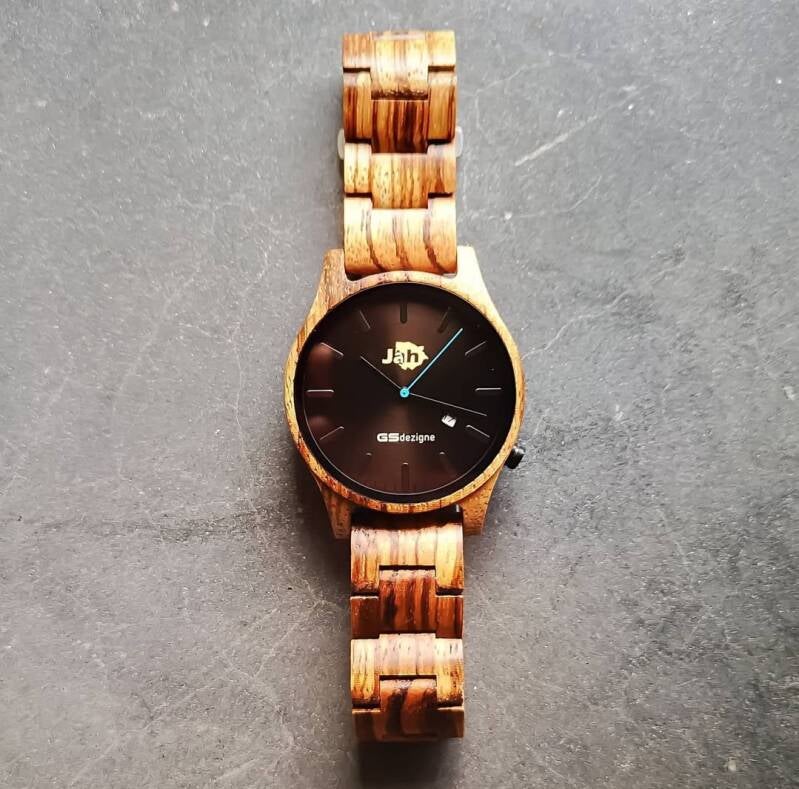 Minimalismo in legno chiaro: orologio JAH a tre lancette con quadrante scuro e indice centrale dorato.