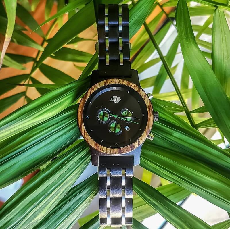 Orologio JAH in legno con cinturino scuro, esposto in un ambiente naturale per evocare l'origine sostenibile dei materiali.